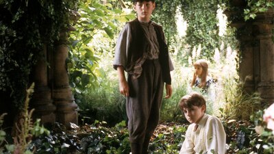 Three young children sitting within a garden