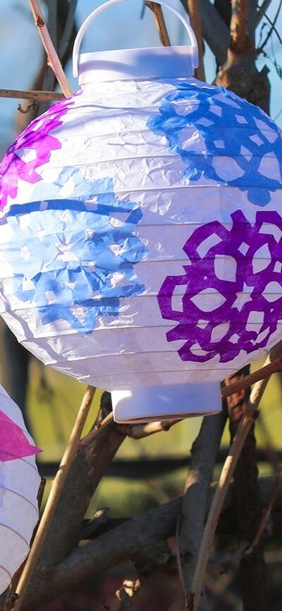 two white lanterns with colourful winter cutout patterns