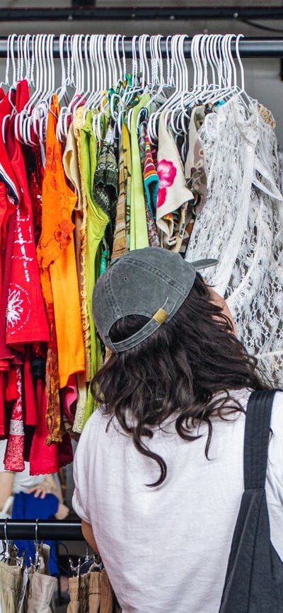 people shopping off of a large colourful clothing rack