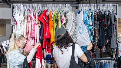 people shopping off of a large colourful clothing rack