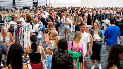 Crowd of people walking through indoor market stalls