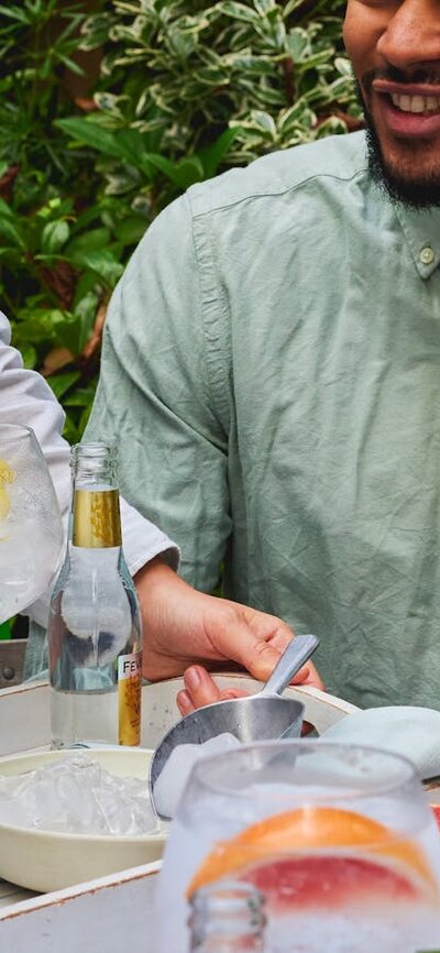 Group of people sitting outdoors, smiling and holding large gin and tonic glasses