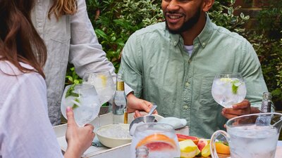 Group of people sitting outdoors, smiling and holding large gin and tonic glasses