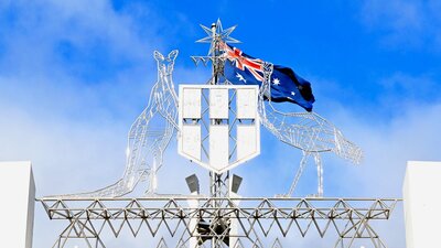 The Australian emblem and Australian Flag set against a blue sky.