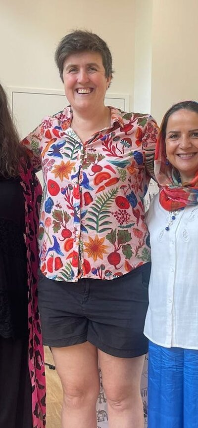 Four women stand before market stalls at the For Purpose Markets