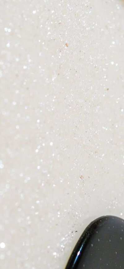 Close up of a glass panel with a white glittery curved shape surrounded by black