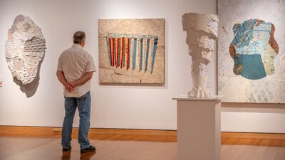 Man observing artworks from Bruce Reynolds ehxibition at CMAG, 2024