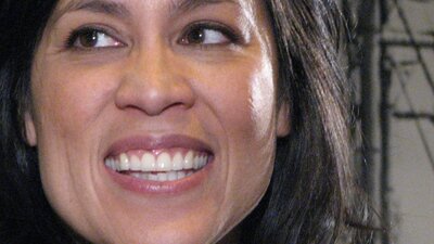 Close -up of Kate Ceberano, smiling, photo of a ship in background