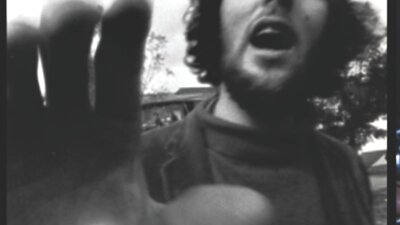 Black and white image of man with hand towards camera and mouth open