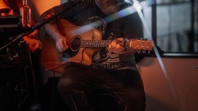 Man wearing hat strumming guitar