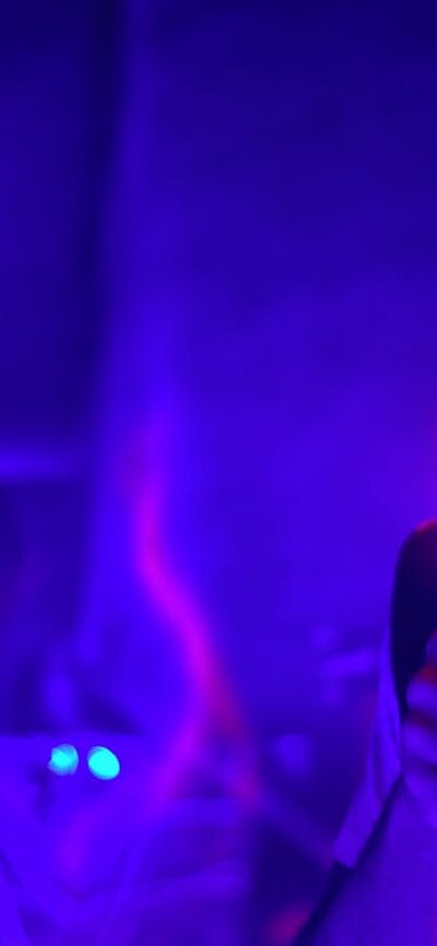 Person aiming laser tag gun in dark arena with neon lights and swirling light effects
