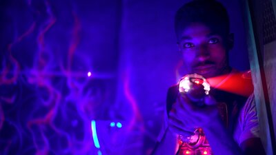 Person aiming laser tag gun in dark arena with neon lights and swirling light effects