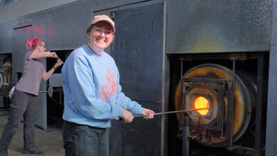Participant in the Glassworks hotshop working with molten glass
