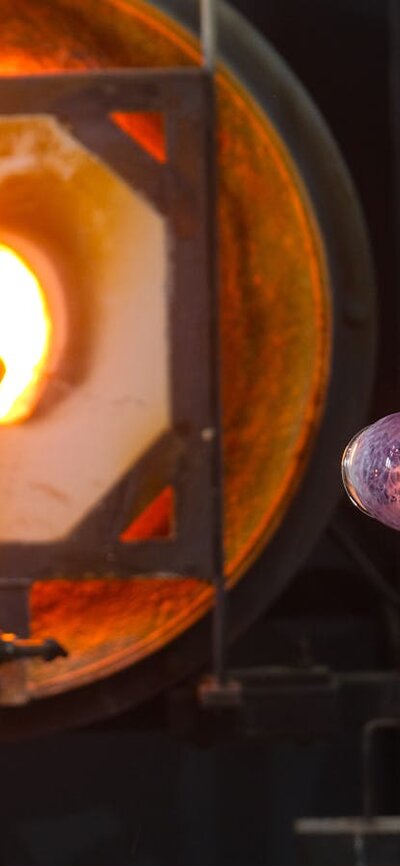 Blown glass tumbler on glass blowing pipe in the Hotshop