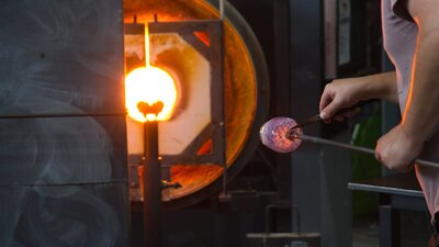 Blown glass tumbler on glass blowing pipe in the Hotshop