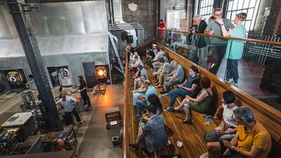 Visitors watching artists blow glass in the Hotshop