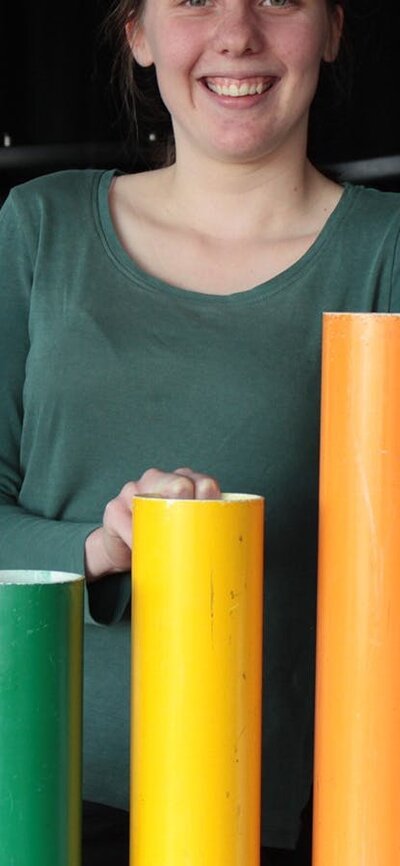 Three kids playing with rainbow percussion tubes