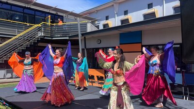 Belly dancers in colourful outfits dancing on an outdoor stage