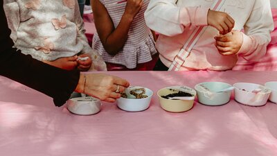 An image of potion ingredients on a table, with kids hands taking the ingredients.
