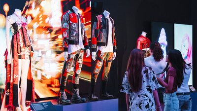Korean fashion being displayed on mannequins in an exhibition and three young girls  looking at them