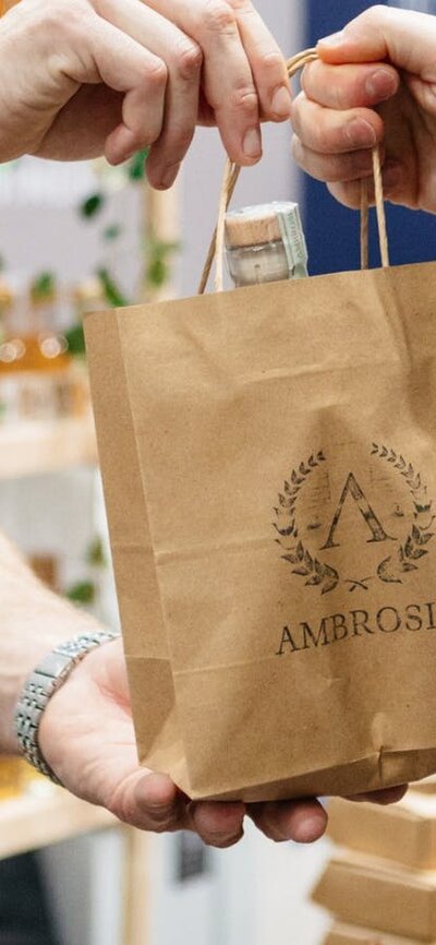 Ambrosia Distillery bag being handed to a customer
