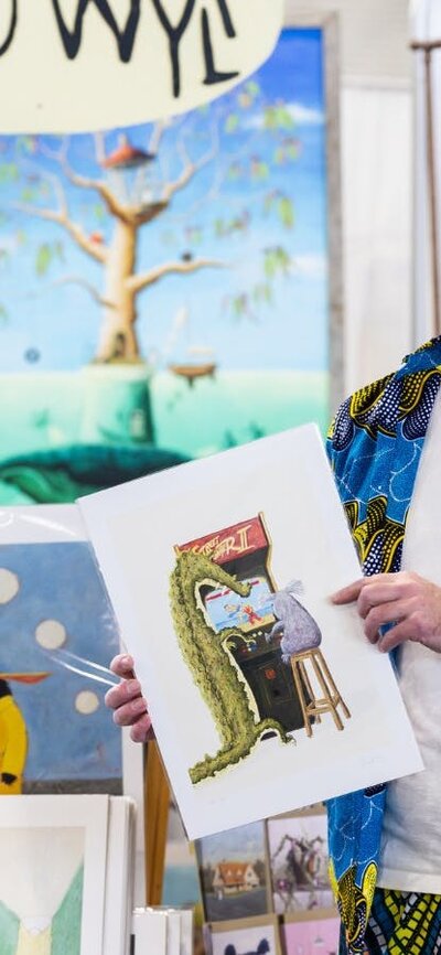 Beau Wylie standing in front of his stall at the Handmade Market Canberra holding his art