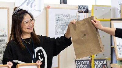 Mary Cheng Art handing a bag over to a customer