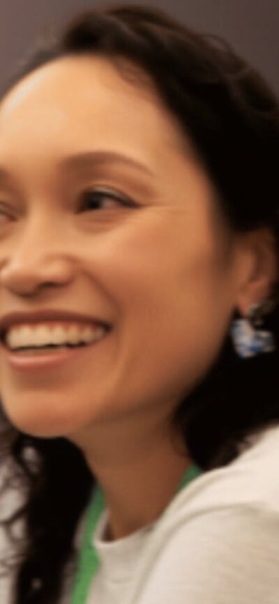 Female doctor smiling, with a green lanyard around her neck.