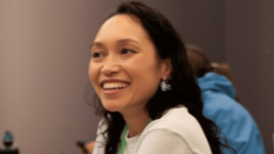 Female doctor smiling, with a green lanyard around her neck.