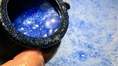 A bath bomb in cauldron, fizzing blue in the bath