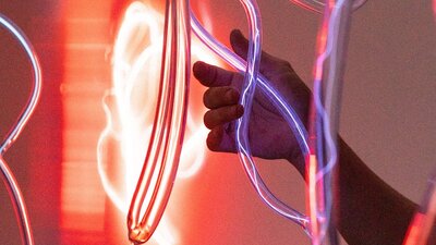 Close up image of suspended bright neon lights with a hand reaching out to touch them