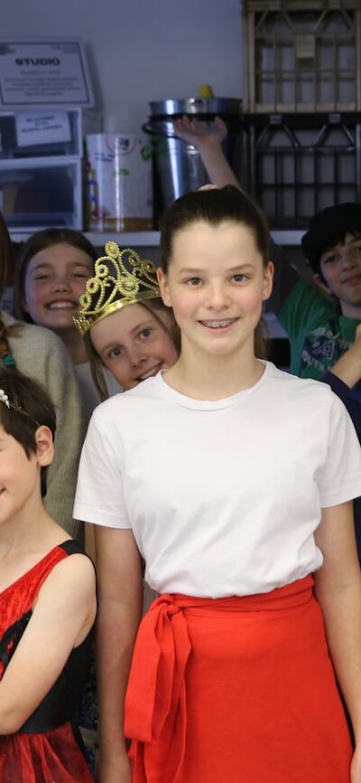 A group of children in various costumes, stand, facing the camera, smiling.