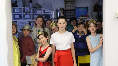 A group of children in various costumes, stand, facing the camera, smiling.