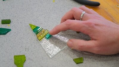 Participant arranging glass tiles in a Christmas tree ornament