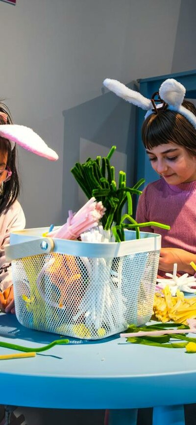 Four children creating objects out of colourful pipe cleaners