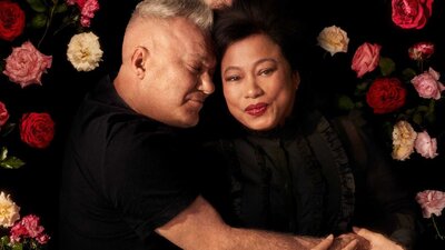 Two adults embracing on a bed of roses.