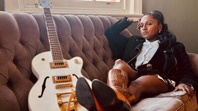 Roshani sitting on lounge with guitar