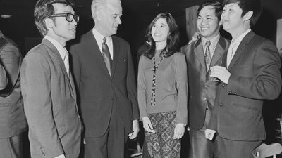Image courtesy of the National Archives of Australia. NAA: A6180, 28/8/72/59. Four men and a woman in conversation while wearing business attire.