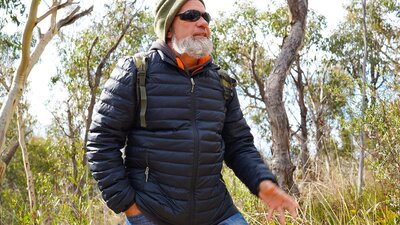 First Nations man Tyronne Bell stands in a heavily grassed eucalyptus forest