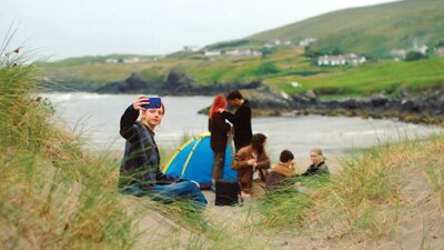 Photo of a boy with his family holding up a phone to take a selfie in the irish countryside