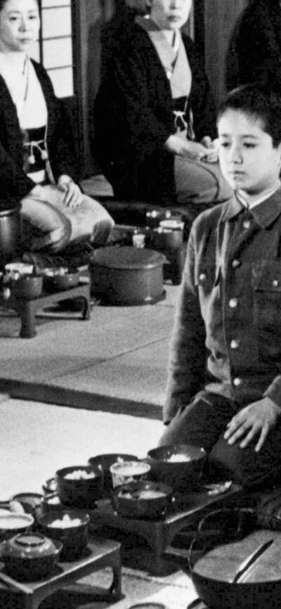 Black and white image of a child seated in the middle of a circle of adults