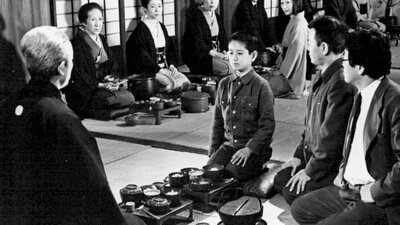 Black and white image of a child seated in the middle of a circle of adults