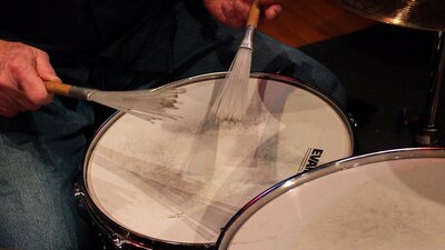 close up of someone playing snare drum with brushes