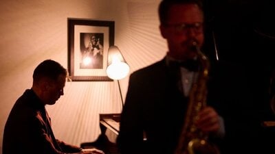 Musicians playing piano and saxaphone in a dimly lit bar