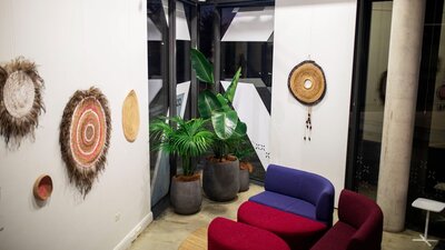 Circular woven art hanging in a room with white walls and red and blue furniture