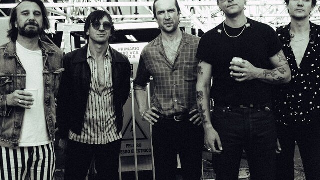 The band membrs from jet standing in a line looking directly at the camera