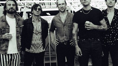The band membrs from jet standing in a line looking directly at the camera