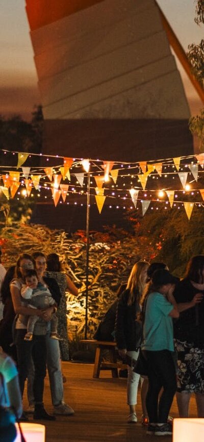Outdoor evening festival with colourful bunting and string lights.