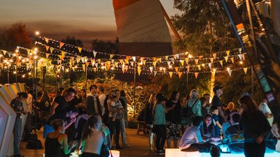 Outdoor evening festival with colourful bunting and string lights.