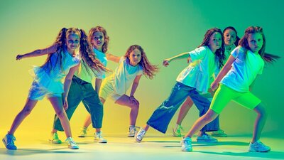 Image of young girls dancing with coloured lighting in background